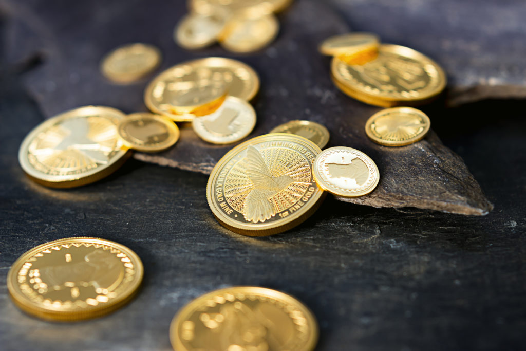 Image shows a selection of Hummingbird investment gold coins, including against a slate background.